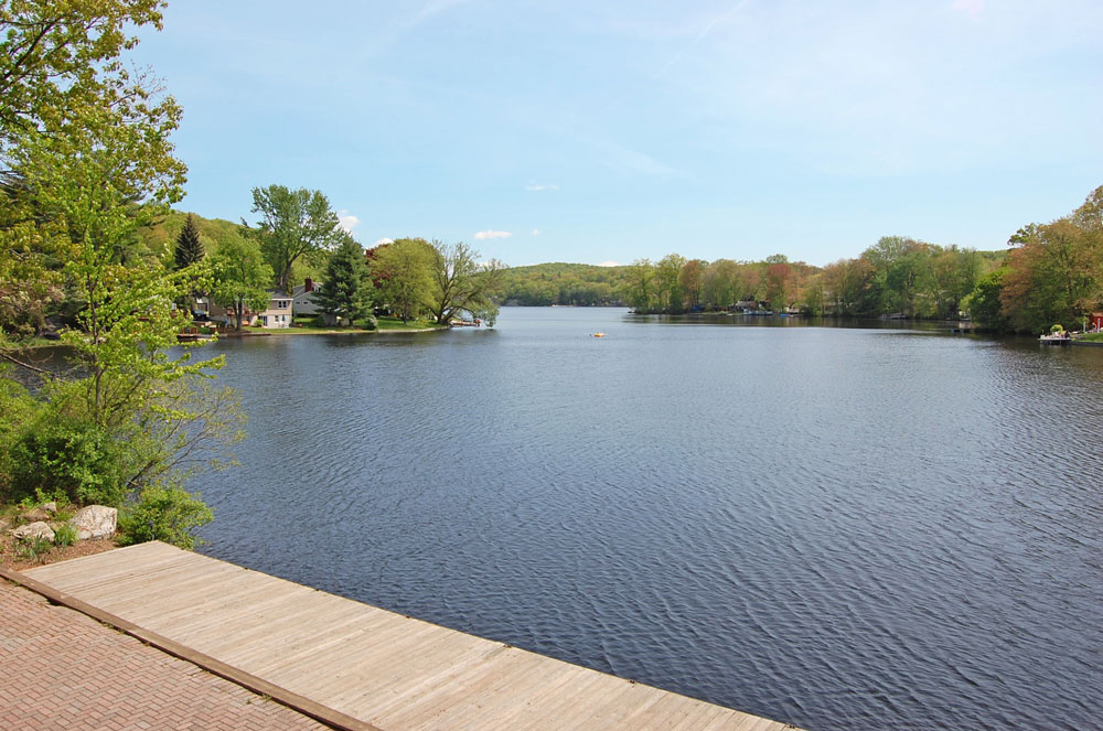 Lake Shawnee's tree-lined shoreline and homes, seen across the water from a wooden dock